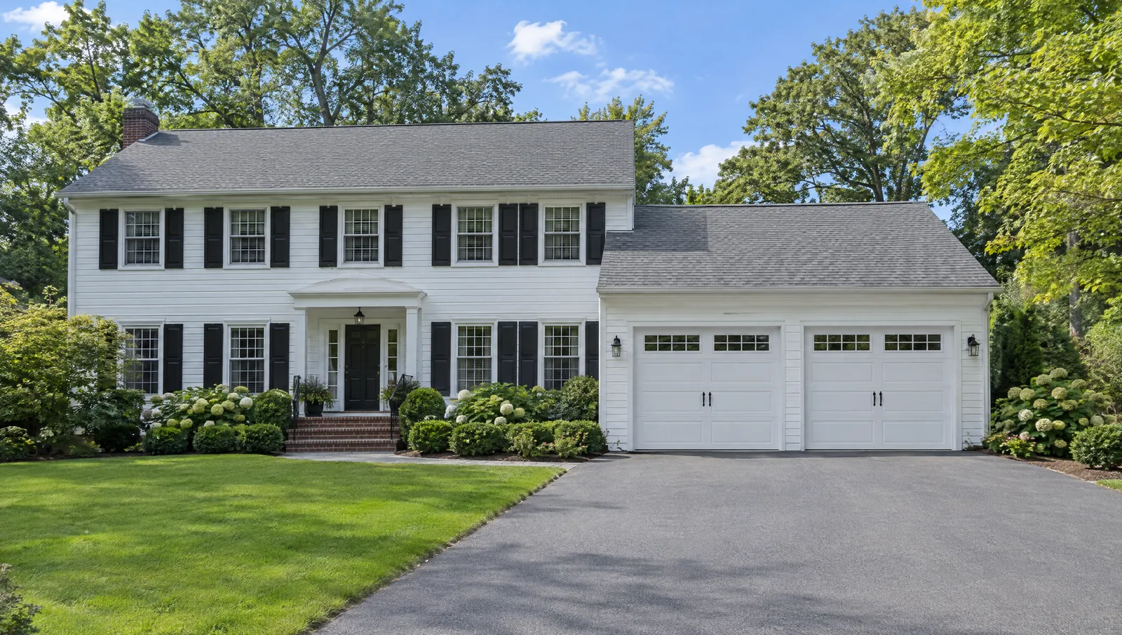White colonial home with a two-car garage and raised-panel garage doors